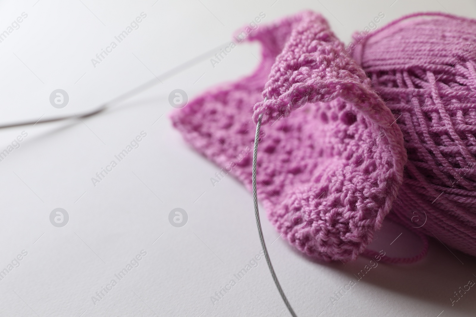 Photo of Knitting, needles and soft pink yarn on light background, closeup. Space for text