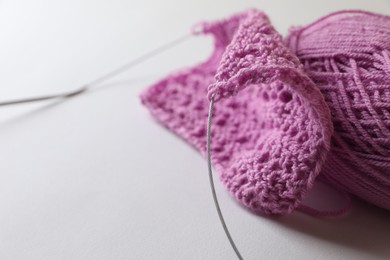 Knitting, needles and soft pink yarn on light background, closeup. Space for text