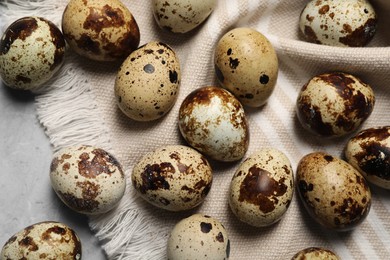 Photo of Many speckled quail eggs on light grey table, flat lay