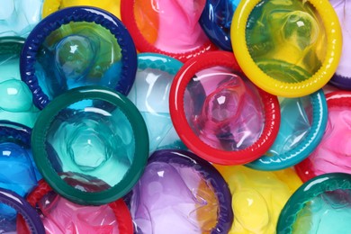 Photo of Colorful unpacked condoms as background, closeup. Safe sex