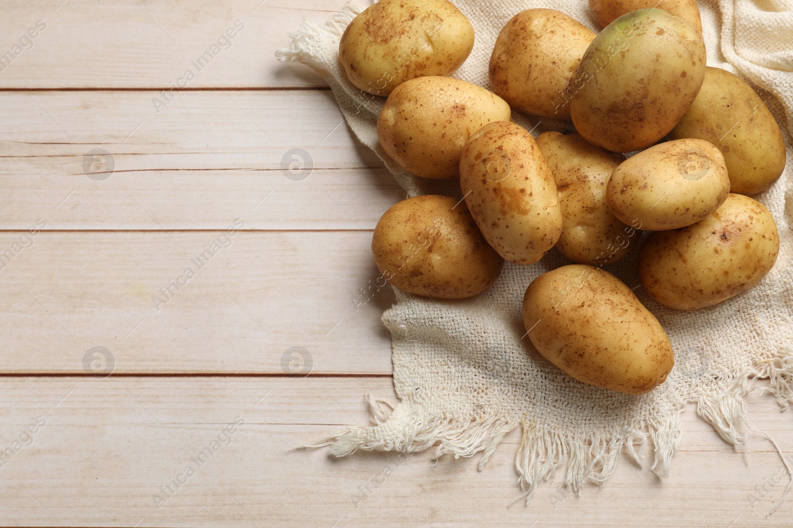 Photo of Raw fresh potatoes on light wooden table, top view. Space for text