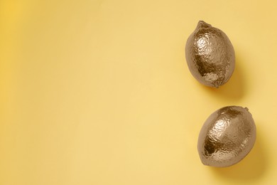 Golden lemons on yellow background, flat lay. Space for text