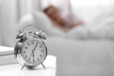 Photo of Woman sleeping at home in morning, focus on alarm clock. Space for text