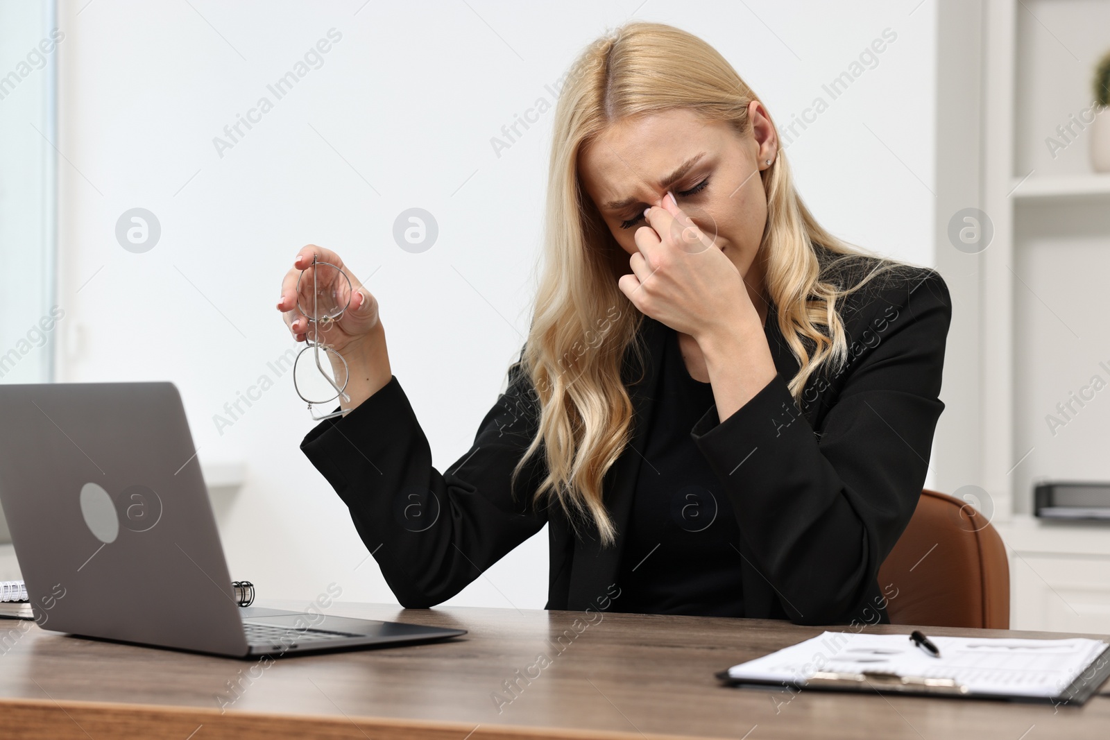 Photo of Overwhelmed woman with glasses at wooden table in office