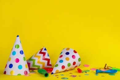 Photo of Colorful party hats and other festive items on yellow background. Space for text