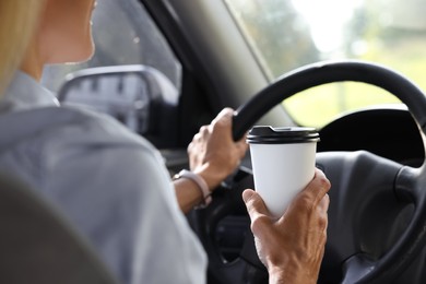 Photo of Coffee to go. Woman with paper cup of drink driving her car, closeup