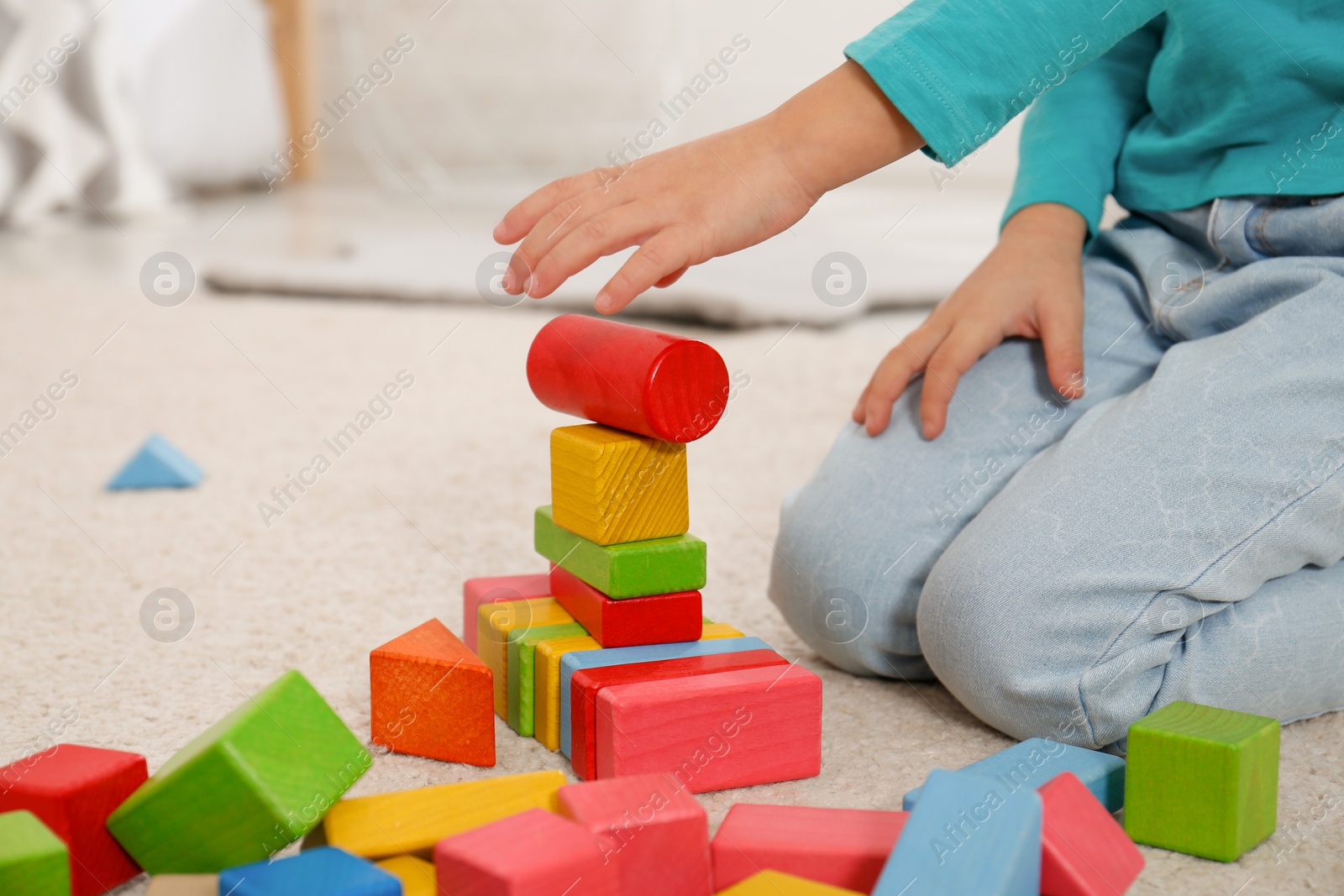 Photo of Cute little girl playing with colorful building blocks at home, closeup