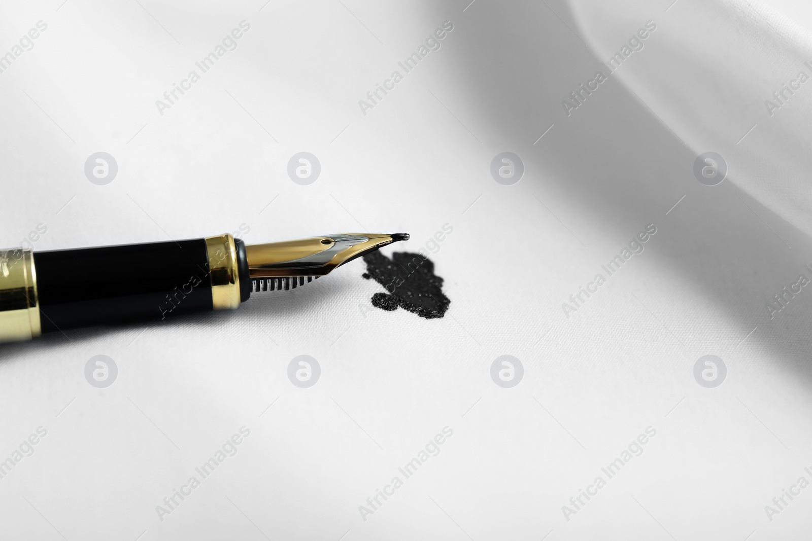 Photo of Pen and stain of black ink on white shirt, closeup. Space for text