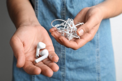 Photo of Woman holding different earphones on light background, closeup