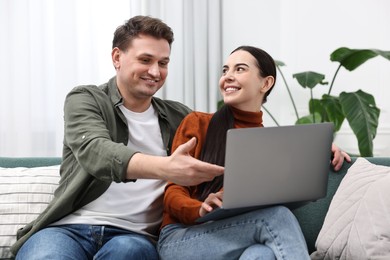 Photo of Happy couple using laptop together at home