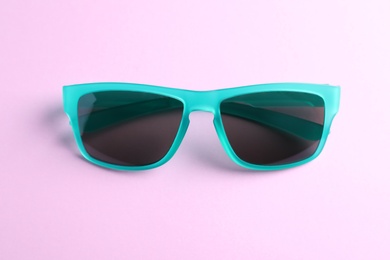 Stylish sunglasses on light violet background. Summer accessory