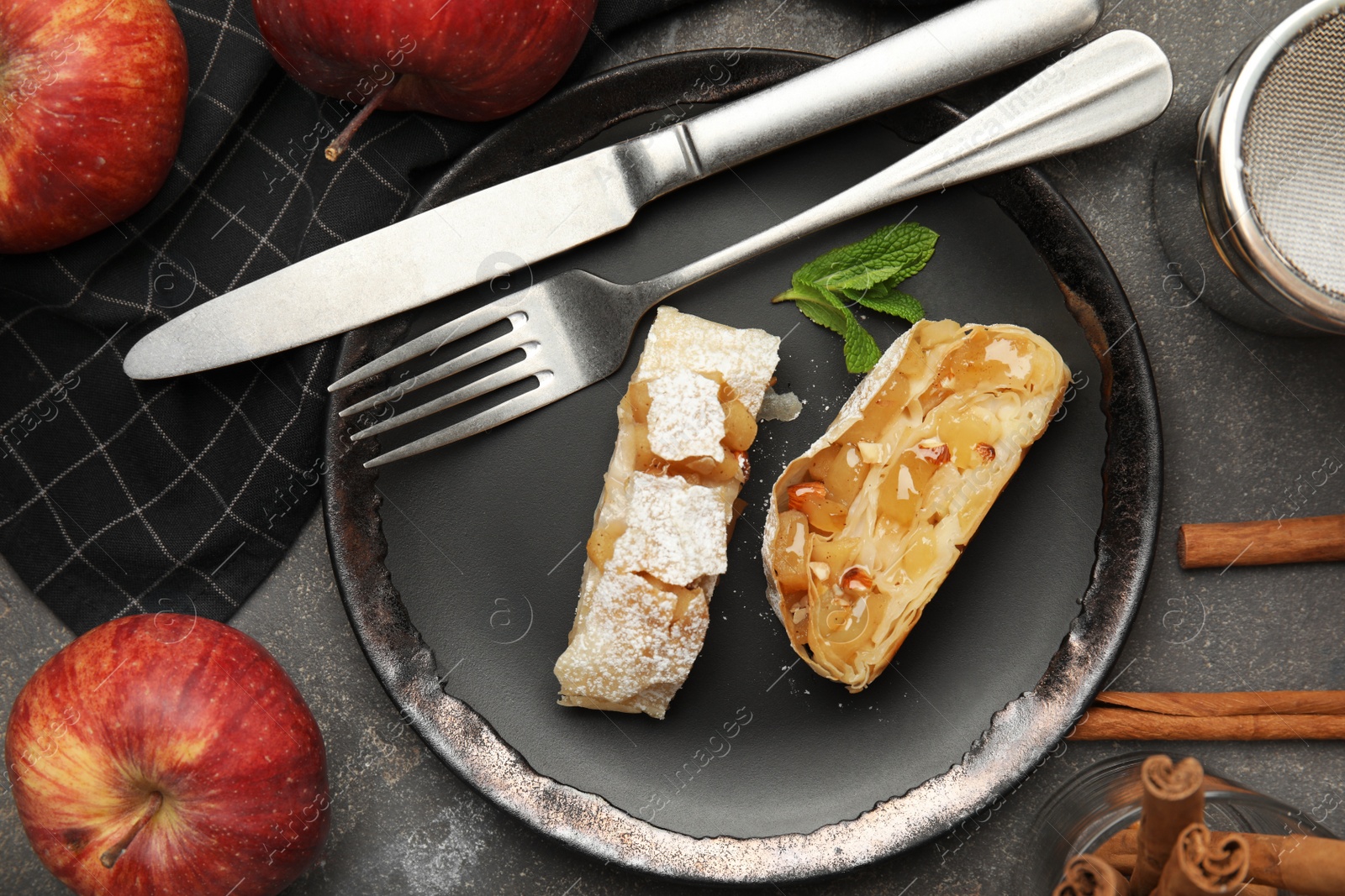 Photo of Delicious strudel, cinnamon and fresh apples on grey table, flat lay