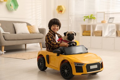 Photo of Little boy with his dog in toy car at home