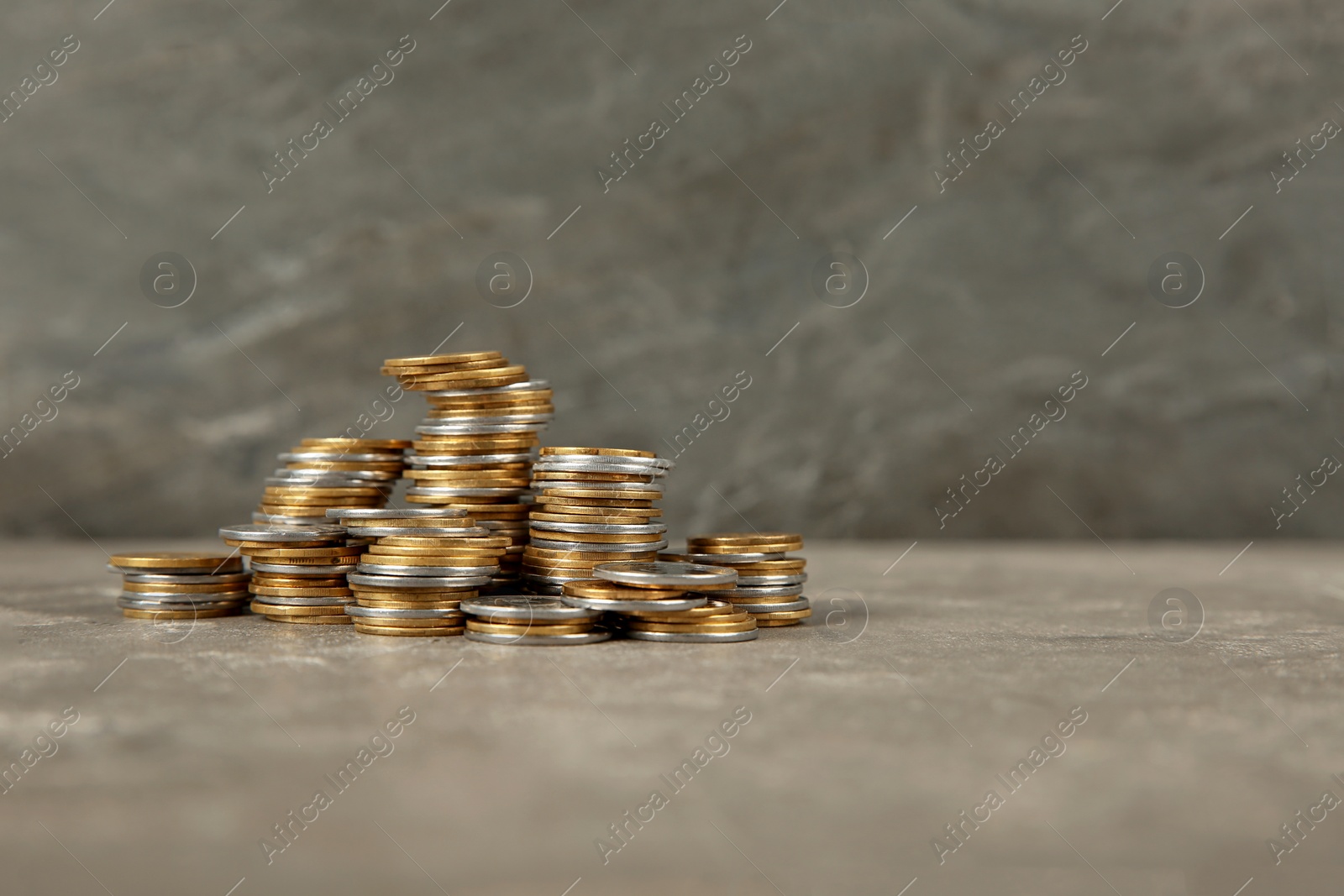 Photo of Stacks of coins on table against color background, space for text