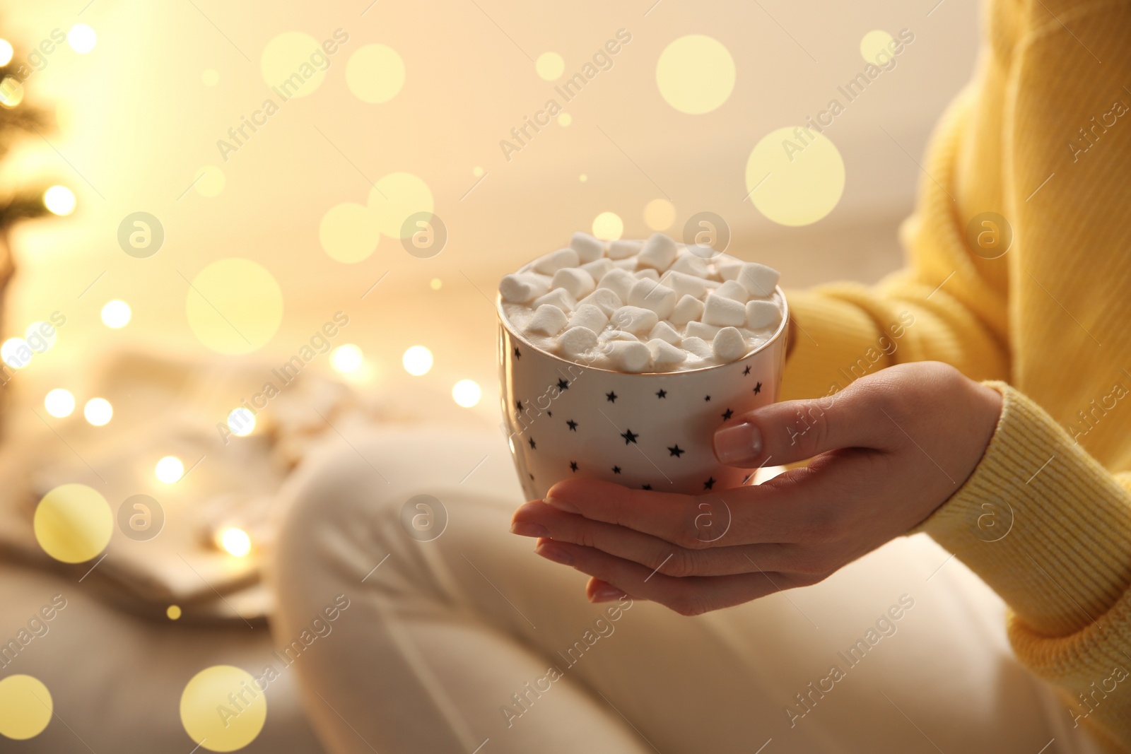 Photo of Woman holding cup of hot drink with marshmallow indoors, closeup