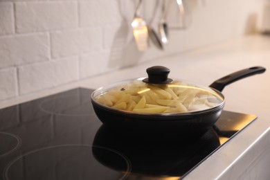 Frying pan with cut raw potatoes on cooktop, space for text