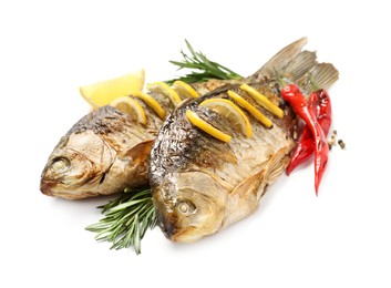 Photo of Tasty homemade roasted crucian carps with rosemary, lemon and chili peppers on white background. River fish