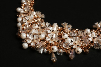 Photo of Stylish necklace on black background, closeup. Luxury jewelry