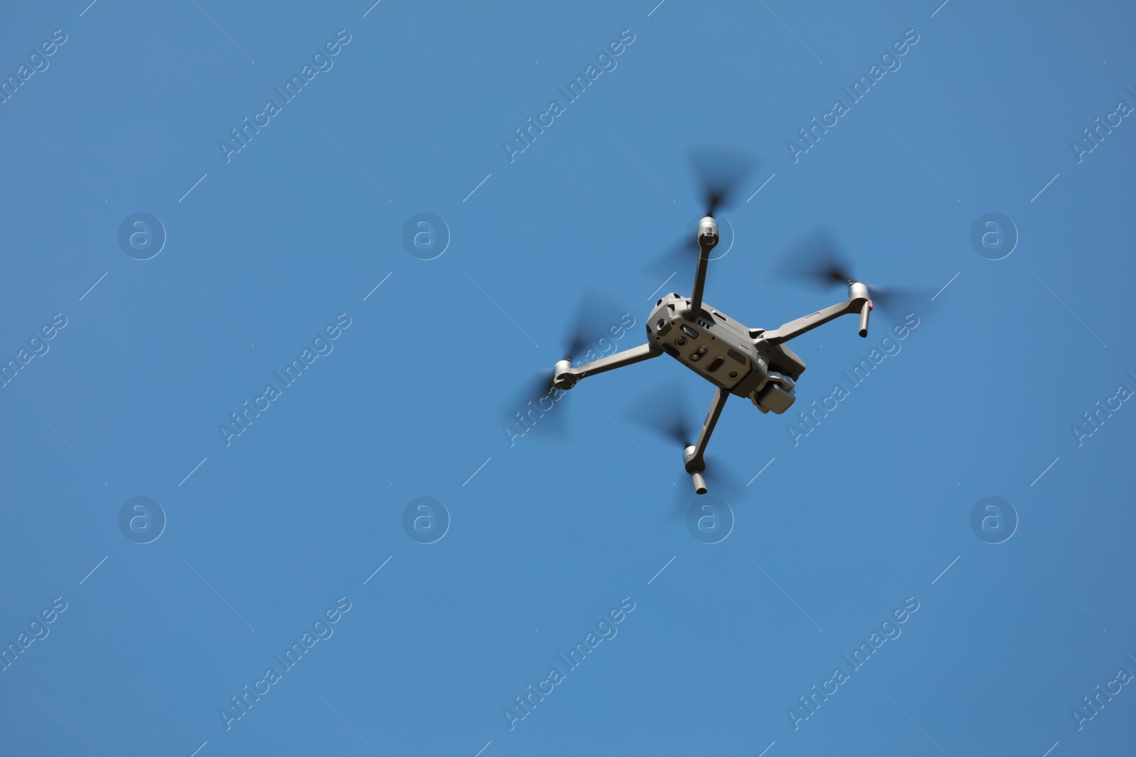 Photo of Modern drone against blue sky, low angle view. Space for text