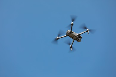 Photo of Modern drone against blue sky, low angle view. Space for text