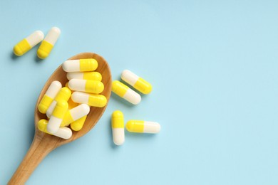 Antibiotic pills and spoon on light blue background, top view. Space for text