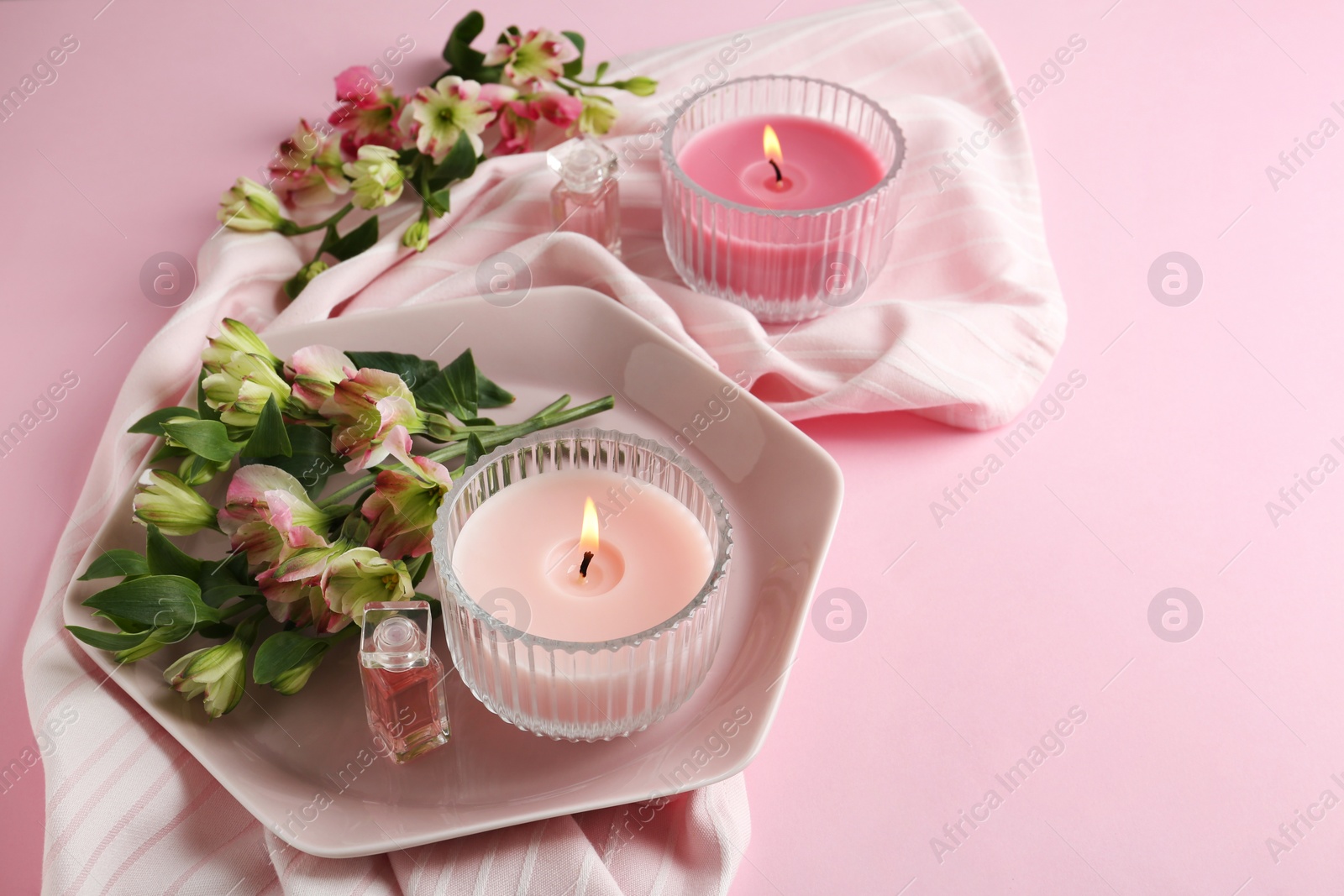 Photo of Stylish tender composition with burning candles and flowers on pink background. Cozy interior element