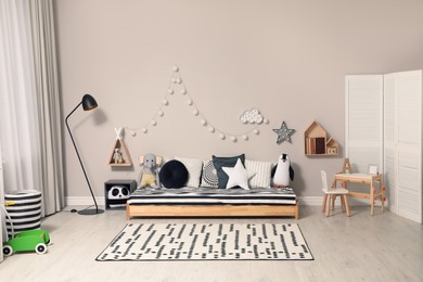 Cute kids room with stylish comfortable floor bed and toys. Montessori interior