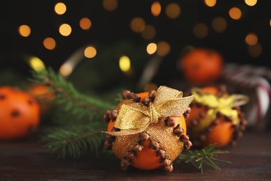 Photo of Pomander ball made of fresh tangerine and cloves on wooden table