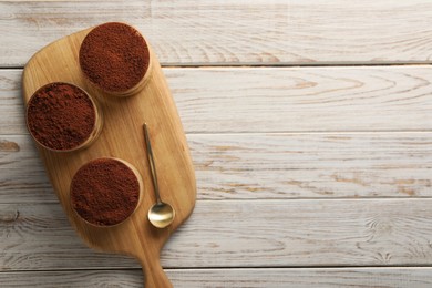 Photo of Delicious tiramisu in glasses and spoon on light wooden table, top view. Space for text