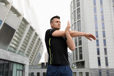 Photo of Young man stretching before morning fitness outdoors