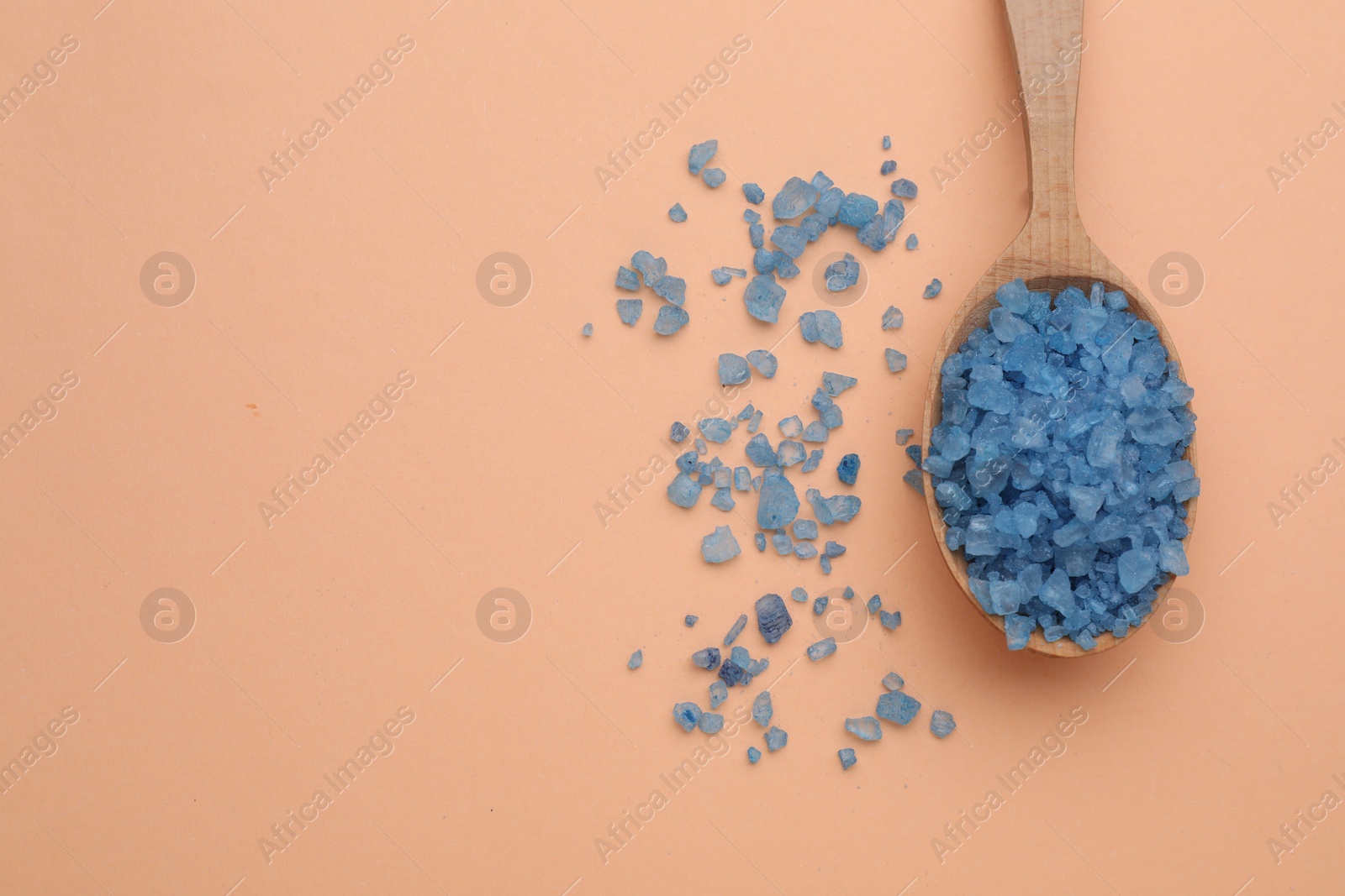 Photo of Spoon with blue sea salt on beige background, top view. Space for text