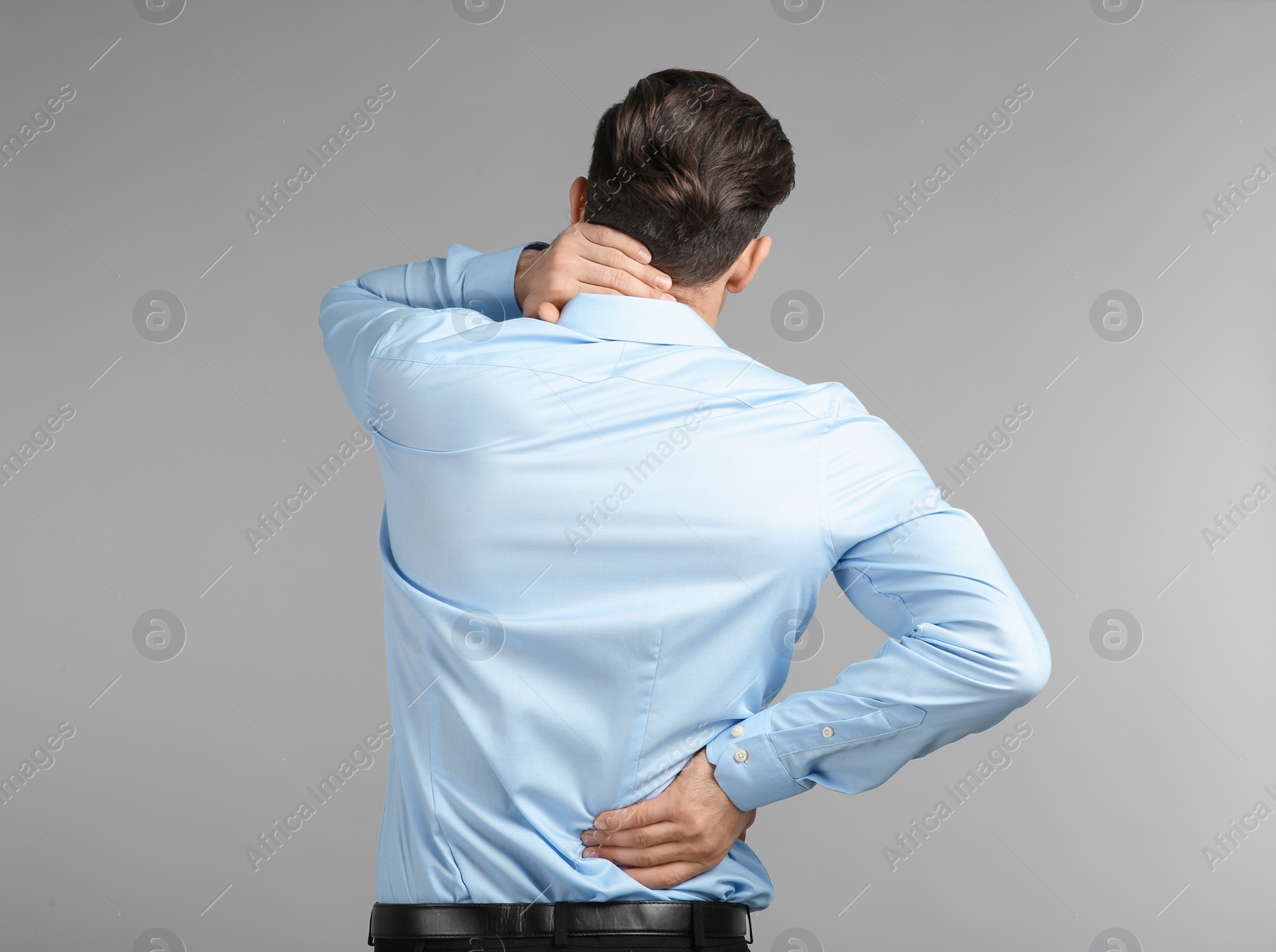 Photo of Young man suffering from neck pain on grey background