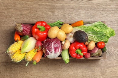 Crate with different fresh vegetables on wooden background, top view