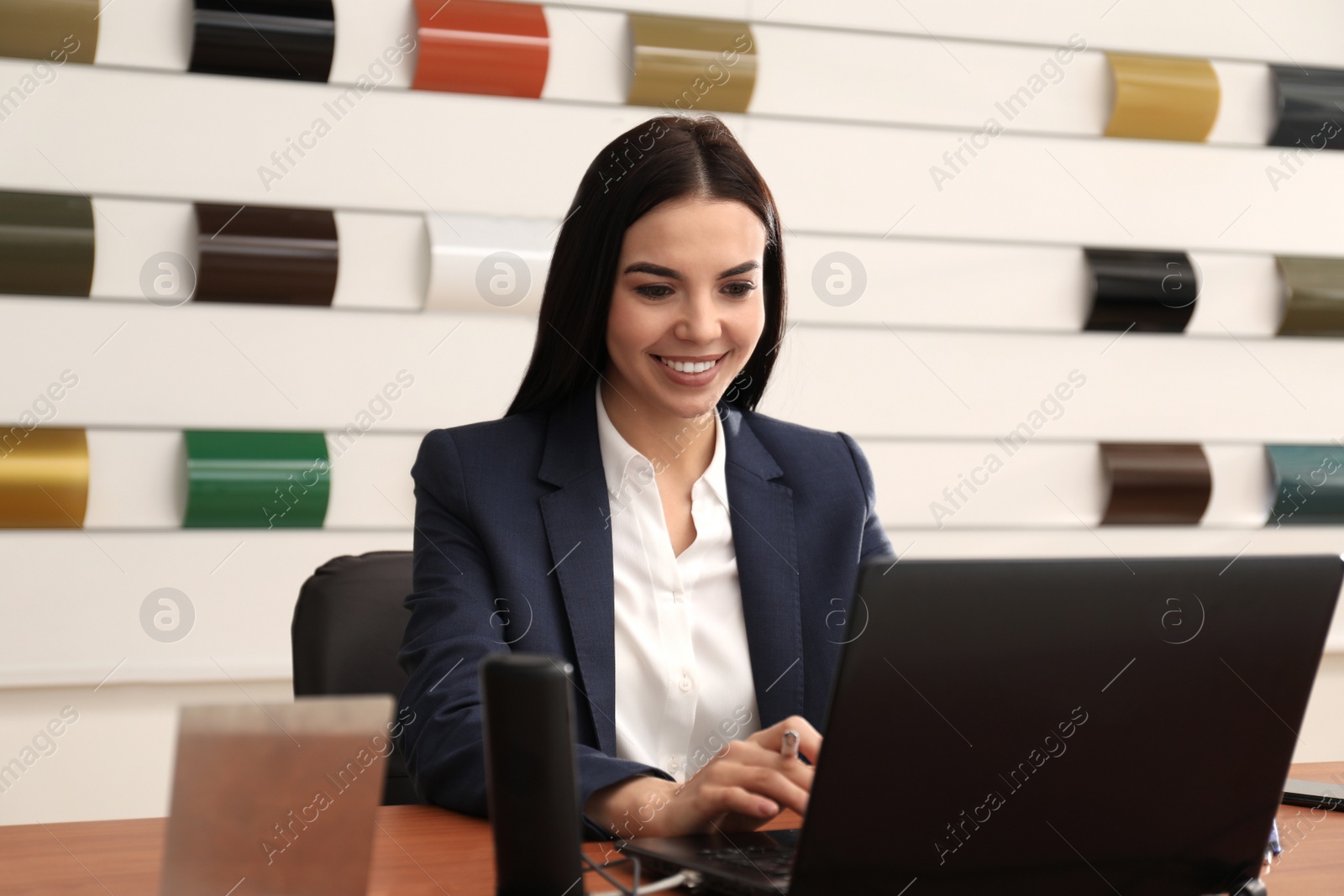 Photo of Saleswoman working with laptop in car dealership