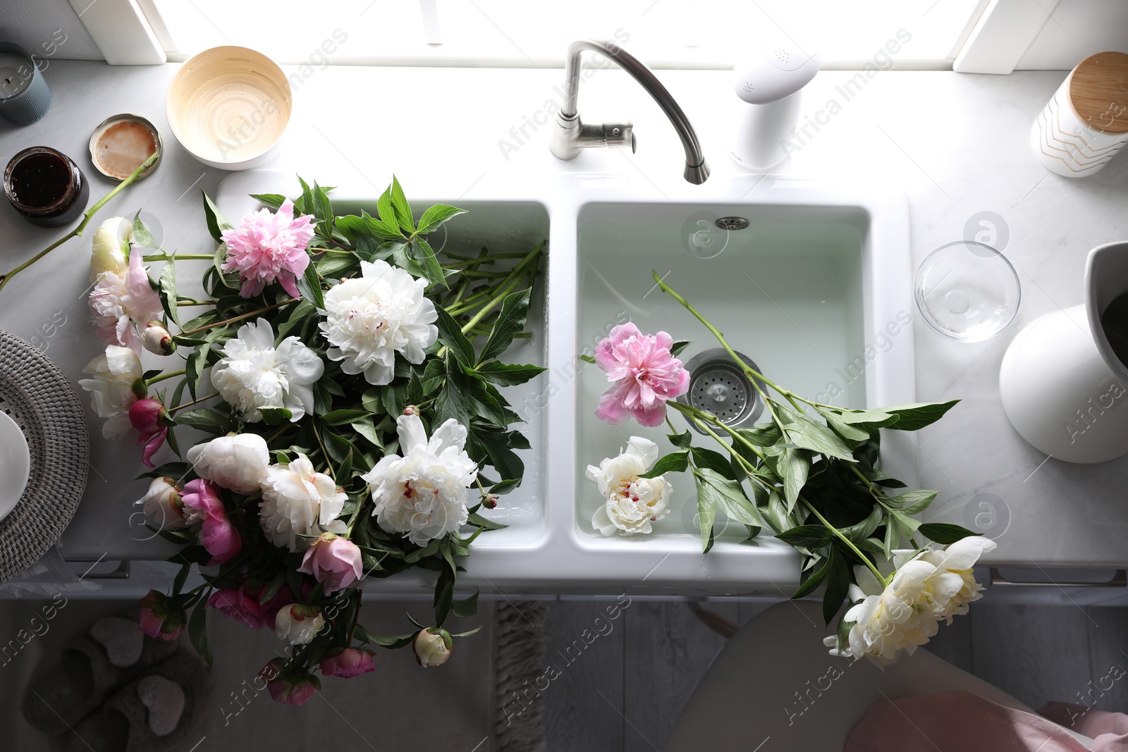 Photo of Bunch of beautiful peonies in kitchen sink, above view