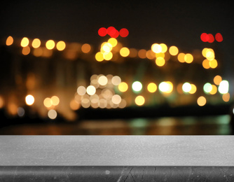 Image of Empty grey marble surface and blurred view of night city. Bokeh effect 