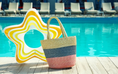 Beach bag and inflatable ring near swimming pool outdoors