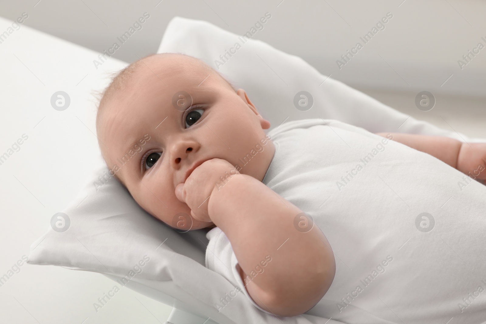 Photo of Cute little baby lying on scales in clinic, closeup