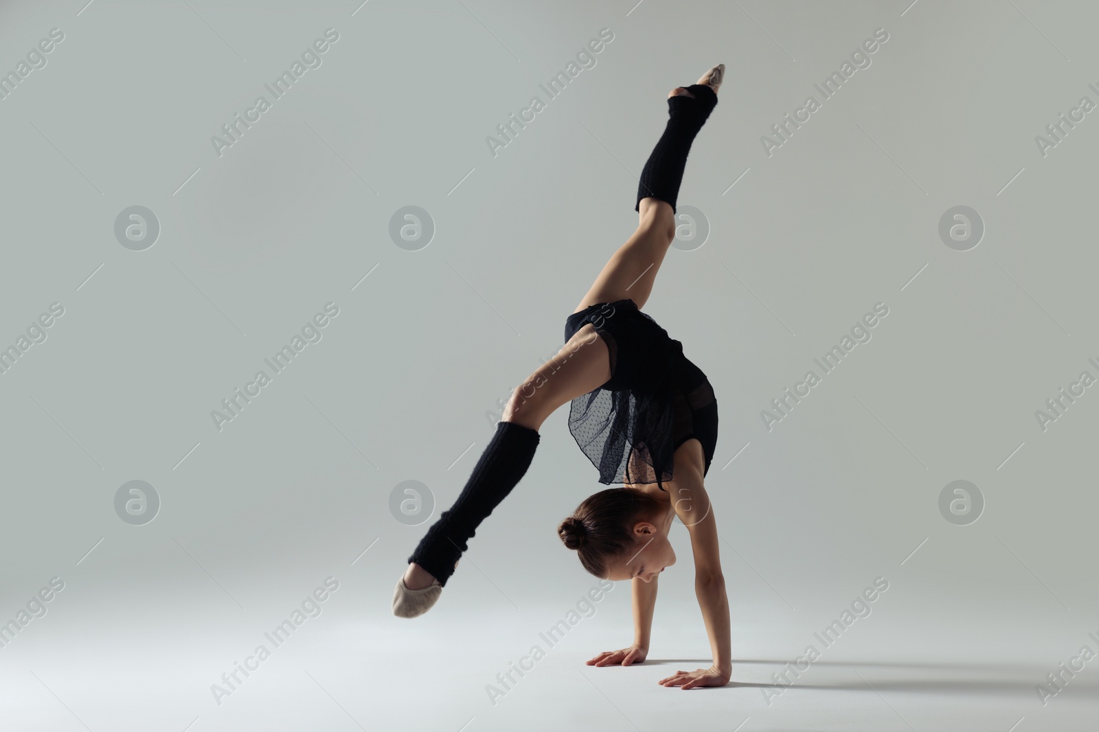 Photo of Cute little gymnast doing handstand on white background