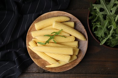 Tasty fresh yellow baby corns on wooden table, top view