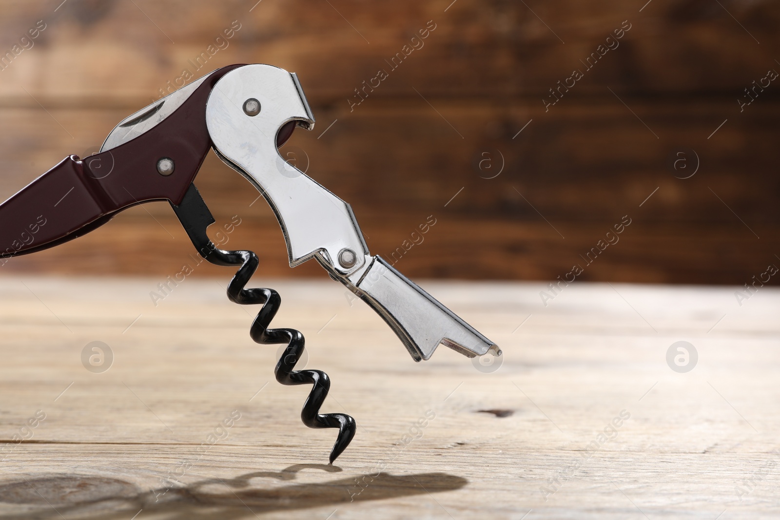 Photo of One corkscrew (sommelier knife) on wooden table, closeup. Space for text