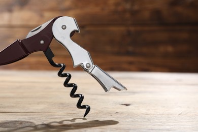 Photo of One corkscrew (sommelier knife) on wooden table, closeup. Space for text