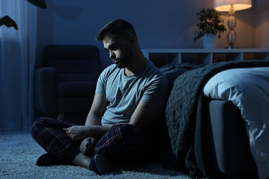 Photo of Frustrated man suffering from insomnia in bedroom at night