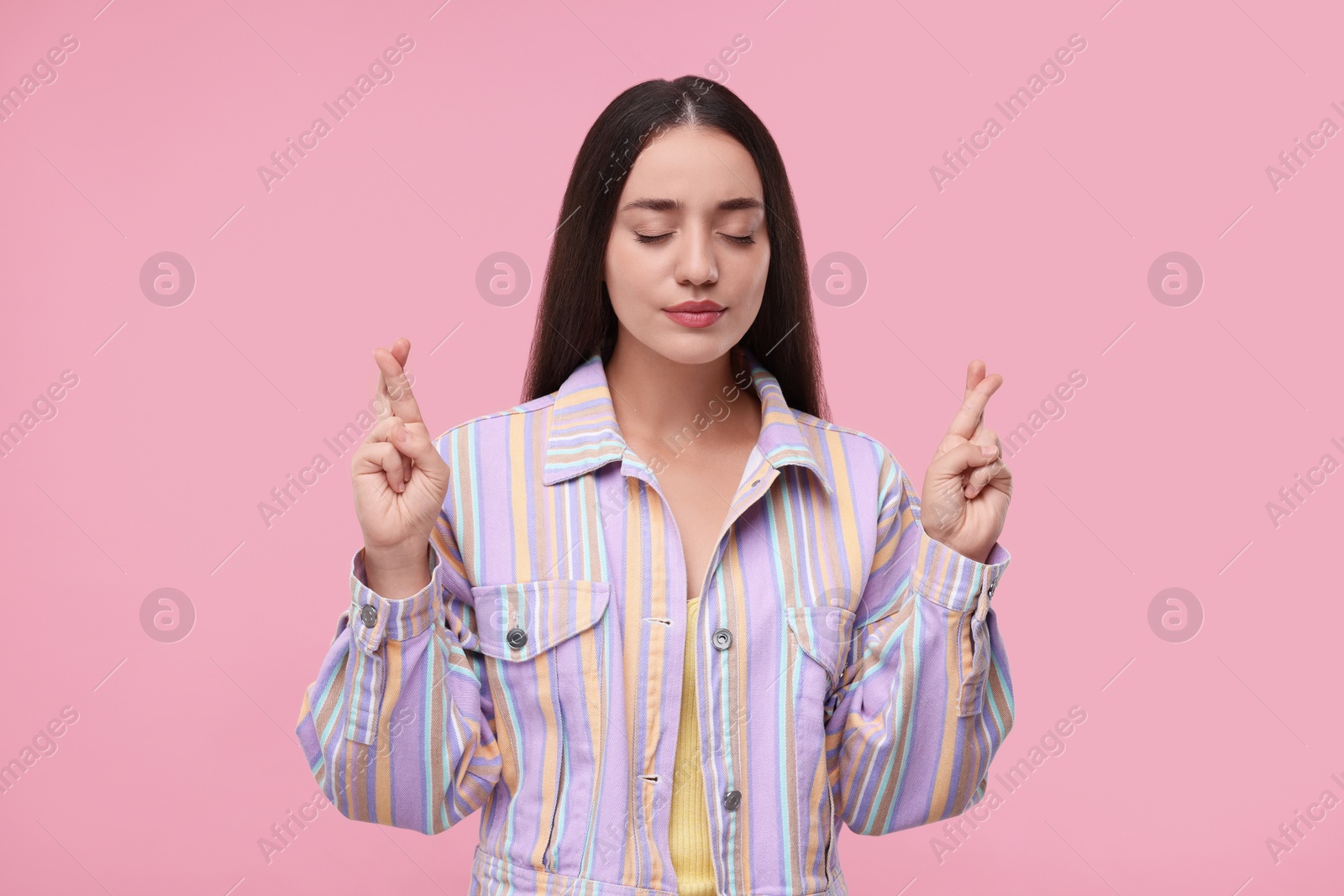 Photo of Beautiful woman crossing her fingers on pink background