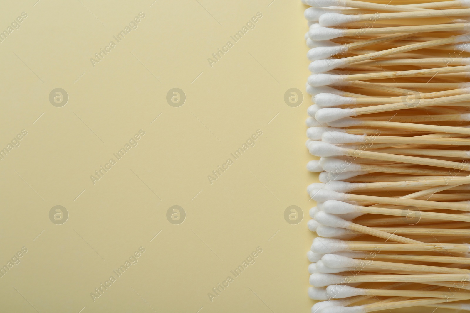 Photo of Many wooden cotton buds on beige background, flat lay. Space for text