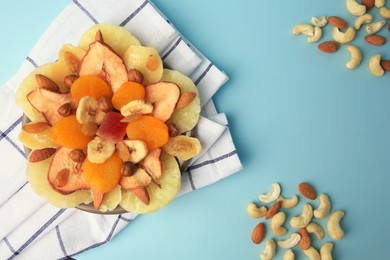 Photo of Mixed dried fruits and nuts on light blue background, flat lay
