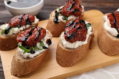 Photo of Delicious bruschettas with sun-dried tomatoes, cream cheese and balsamic vinegar on table, closeup