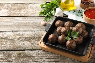 Tasty cooked meatballs with parsley on wooden table. Space for text