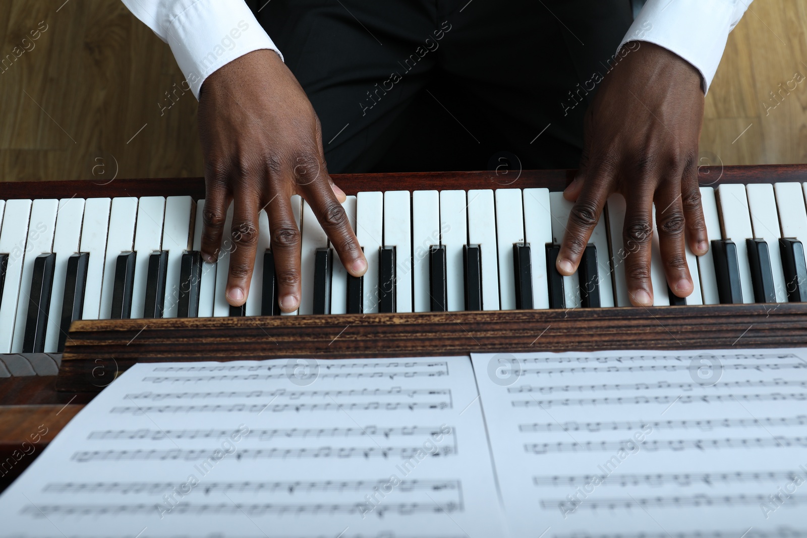 Photo of African-American man playing piano indoors, above view. Talented musician