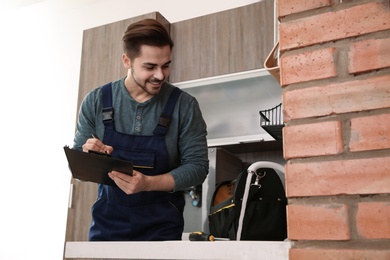 Male plumber with clipboard near kitchen sink. Repair service